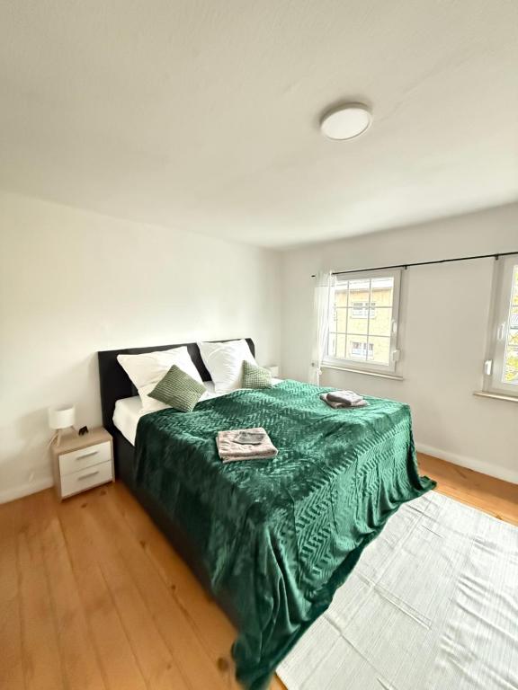 a bedroom with a bed with a green blanket on it at Gästezimmer in Hafennähe in Waren