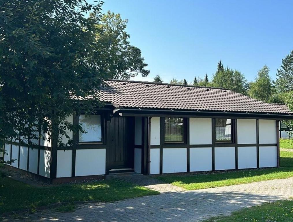 a white and black building with a tree at Ferienhaus Katzenbuckelblick in Waldbrunn