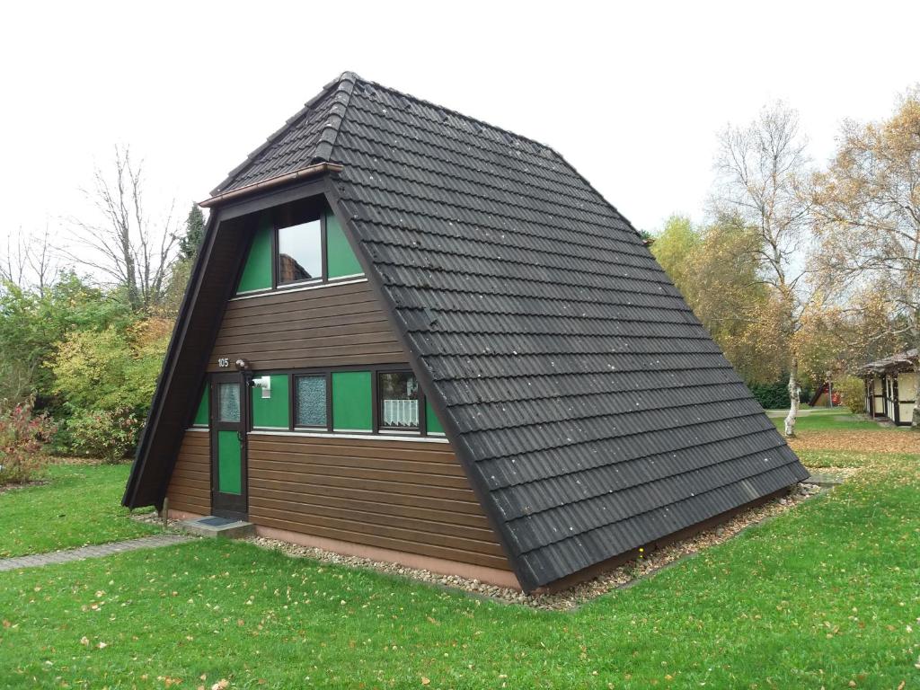 a house with a black roof on the grass at Ferienhaus Winterruhe in Waldbrunn