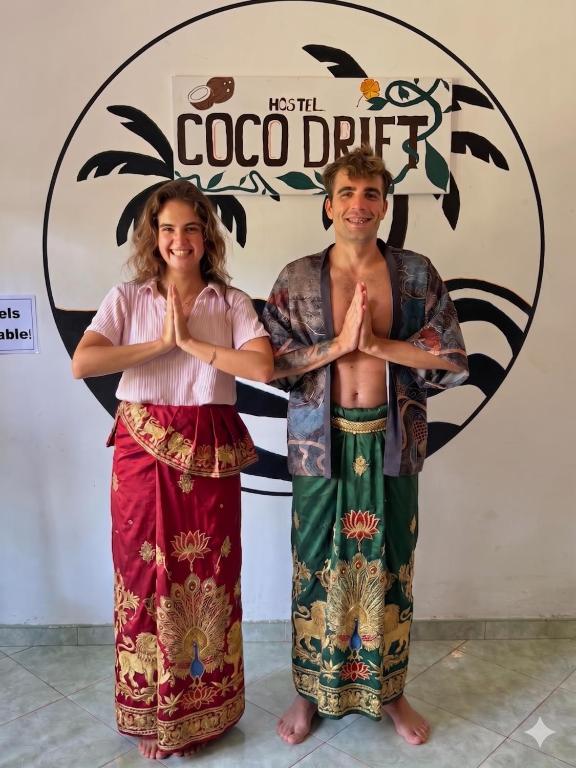 a man and a woman standing in front of a sign at Coco Drift Hostel Hiriketiya in Hiriketiya