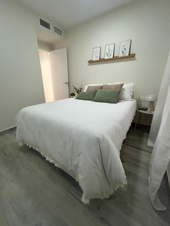 a white bedroom with a large bed with white sheets at Hernández Central Park in Melilla