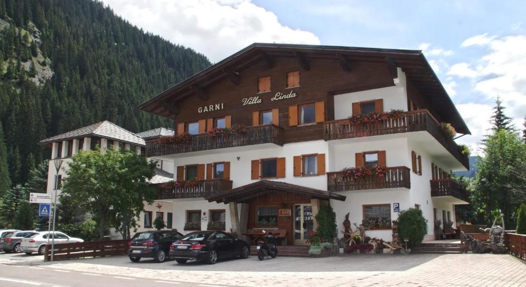a large building with cars parked in front of it at Garni Villa Linda in Corvara in Badia