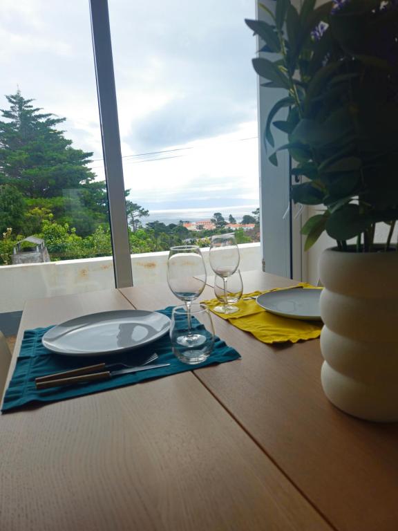 a table with a plate and two wine glasses at Residencias Requinte T3 Espacoso com Terraco e Vista in São Roque do Pico