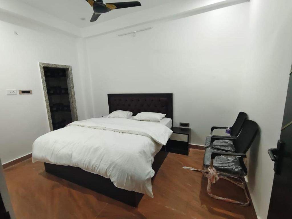 a bedroom with a bed and a black chair at Ma SAVITRI PALACE in Ayodhya
