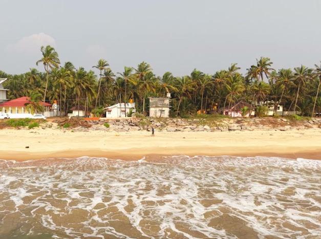 a beach with a group of houses and palm trees at Mannath lands end Beach house in Kaup