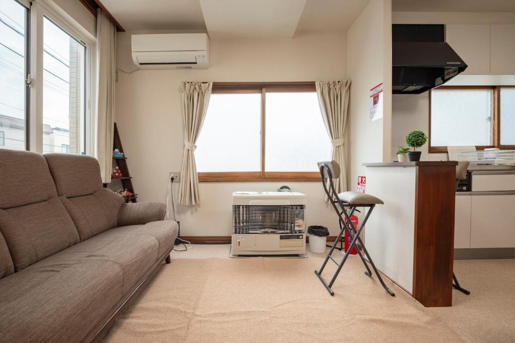a living room with a couch and a kitchen at Otaru Retro Villa in Otaru