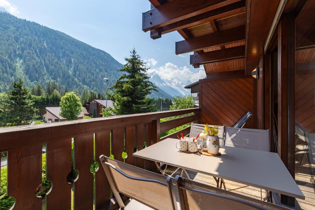 a balcony with a table and chairs and mountains at Chalet Résidence Chantey Mourry in Argentiere