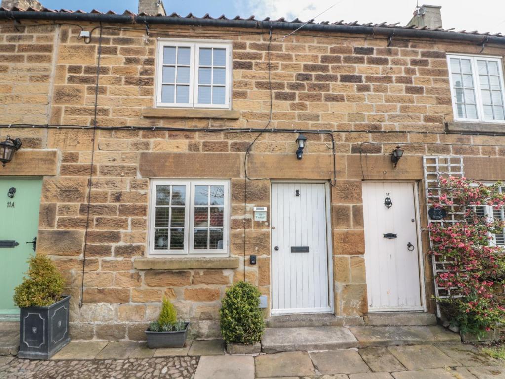 an old brick house with two white doors at Isla cottage in Northallerton
