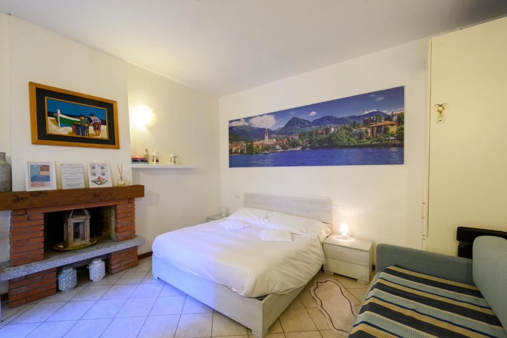 a bedroom with a white bed and a fireplace at Gigi House in Verbania