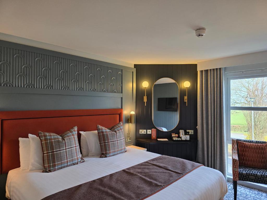 a bedroom with a large bed and a mirror at Smiths At Gretna Green Hotel in Gretna Green