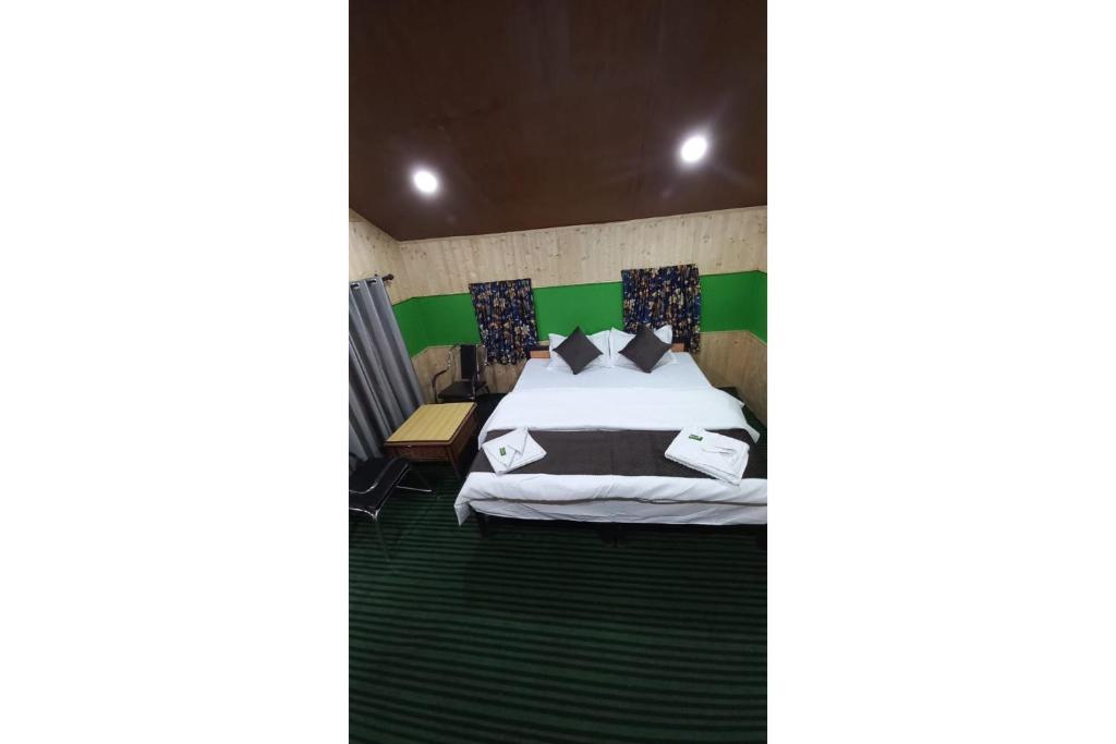 a bedroom with a bed with a green headboard at Thrillomania Kasol in Kasol