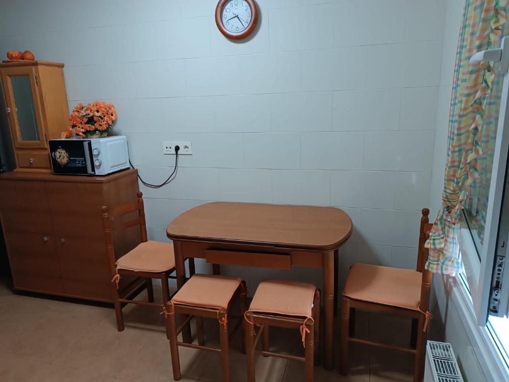 a small table and chairs in a room with a clock at Apartamento Ria de Vegadeo in Vegadeo