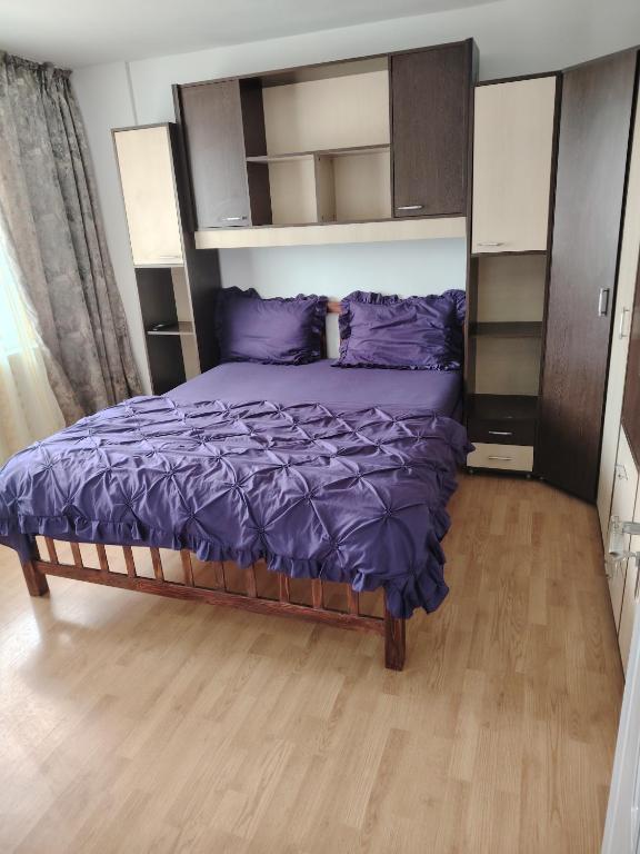 a bedroom with a large bed with purple sheets at Apartament in Geoagiu Băi