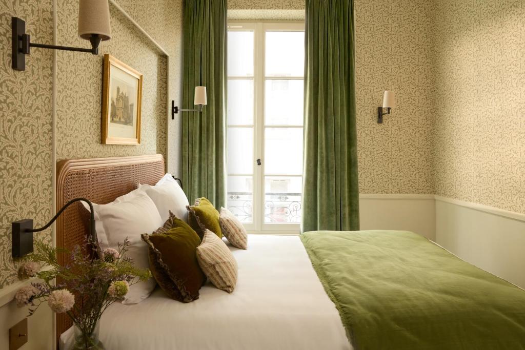 a bedroom with a bed with green curtains and a window at Hotel des Orfèvres in Paris