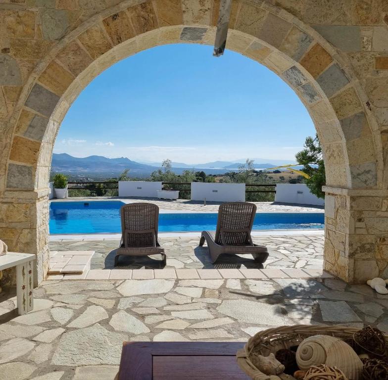 an archway with two chairs and a swimming pool at Mediterranean Villa Megara in Megara