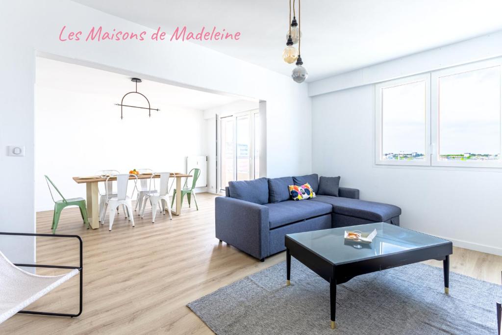 a living room with a blue couch and a table at Nouveau - Horizons - Vue mer in Saint-Nazaire