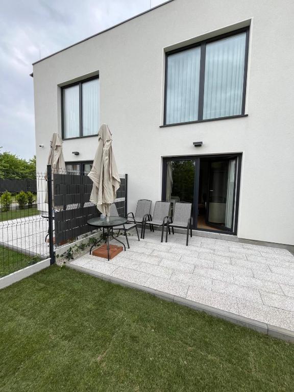 a house with a patio with chairs and an umbrella at Głębinów Apartamenty nad jeziorem nyskim in Głębinów
