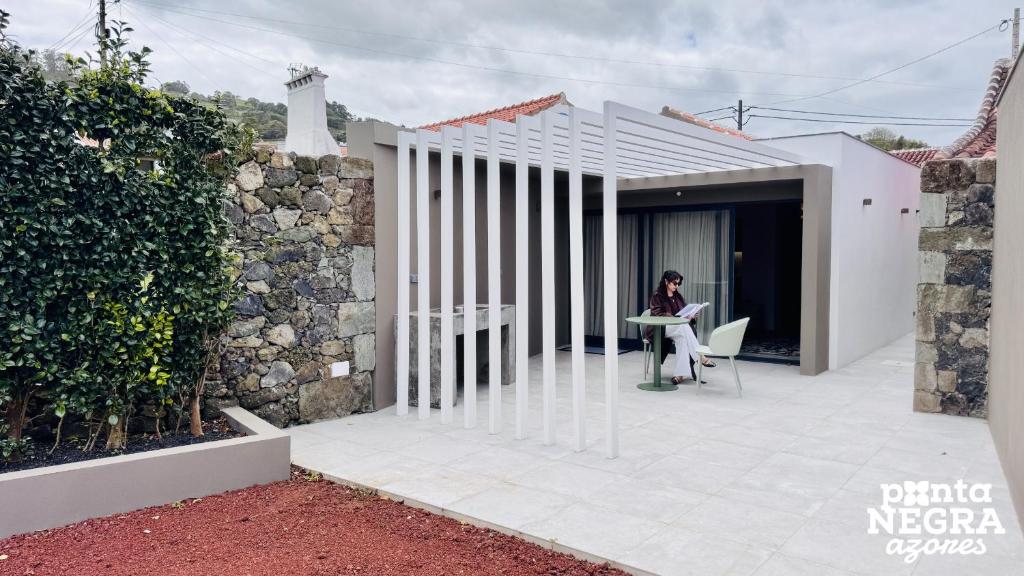 a woman sitting at a table outside of a house at O Palheiro in Biscoitos
