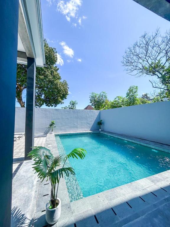a swimming pool with a palm tree next to a house at X Hostel Jogja in Timuran