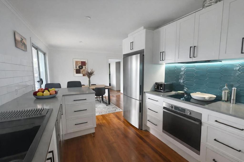 a kitchen with white cabinets and a blue accent wall at Poolside on the Plateau in Wollongbar