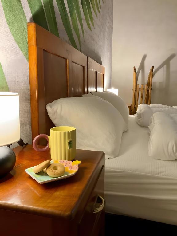 a bed with a table with a plate of donuts and a cup on it at Edelweiss Alp Rooms in Castello Tesino