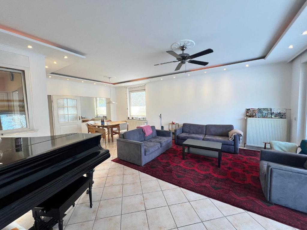 a living room with a piano and couches at Große Terrassenwohnung mit Seeblick in Stechlin