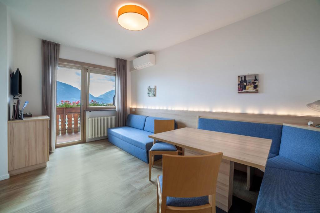 a living room with a blue couch and a table at Gartenheim App Verena in Schenna