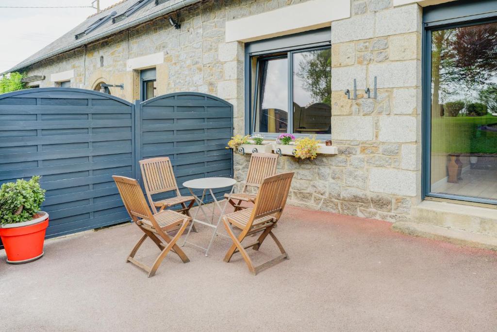 a patio with three chairs and a table in front of a building at La maison de la Rebergère in Javené