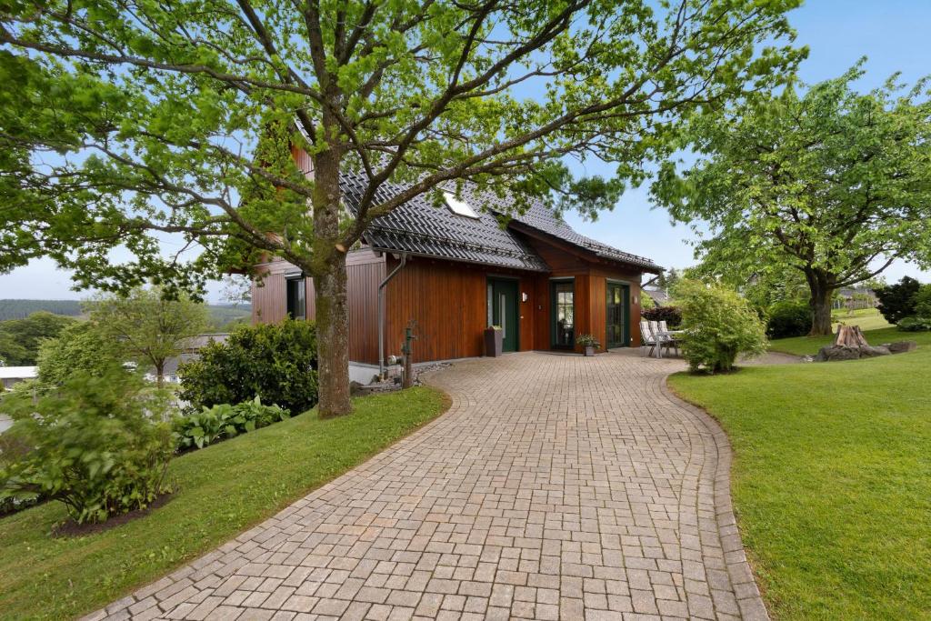 a brick driveway leading to a house with a tree at Ferienhaus Wasserfall in Bestwig