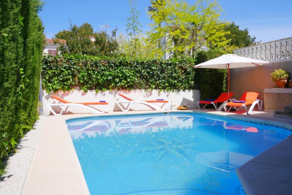 a swimming pool in a yard with chairs and an umbrella at Ca Na Cati in Muro