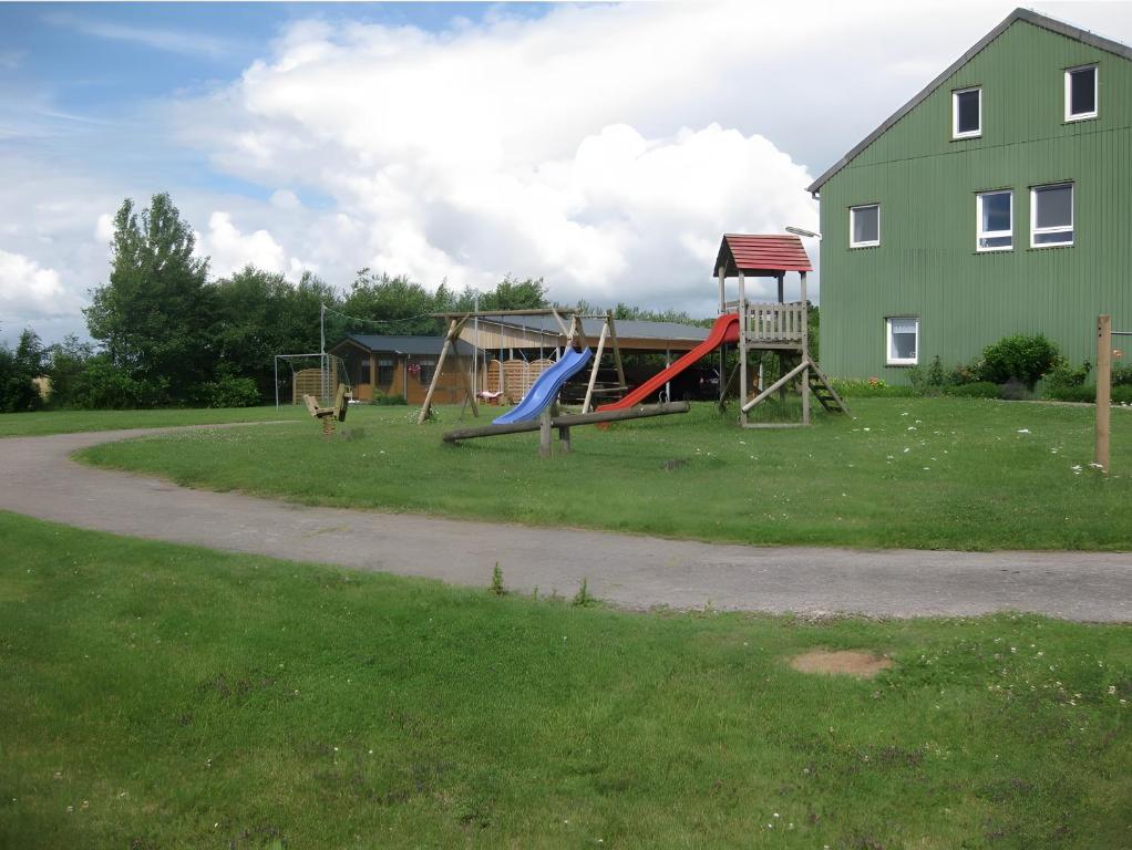 a playground with a slide and a swing set in a yard at Ferienwohnungen Carstensen in Nordstrand