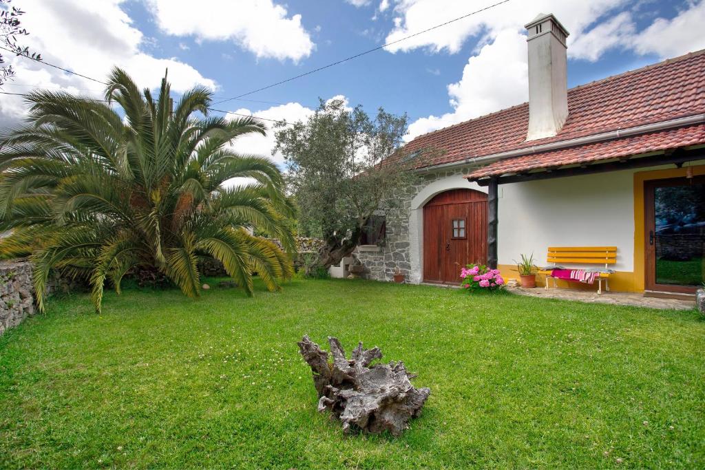 a house with a yard with a tree stump at Casa do Largo in Mendiga