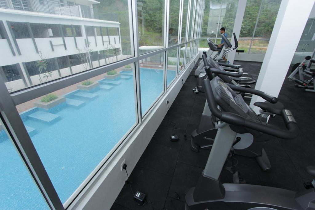 a row of exercise bikes in a gym with a pool at Nabiha Suites Bandar Baru Bangi in Bangi