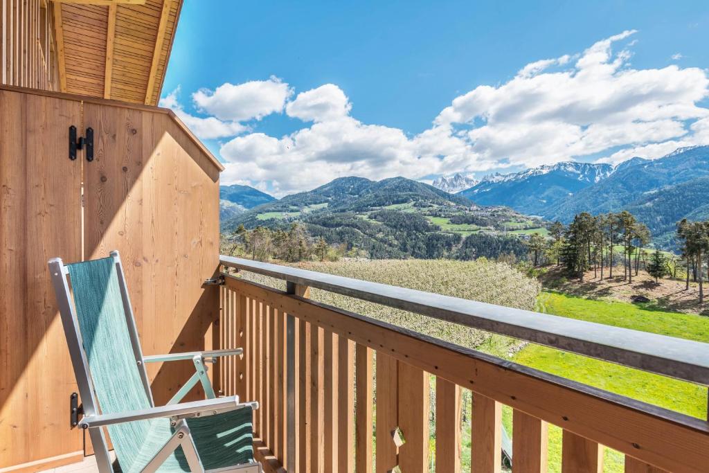 a rocking chair on a porch with a view of mountains at Huberhof Appzimmer in Feldthurns