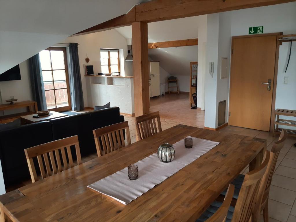 a dining room and living room with a wooden table at Fewo beim Schmied Straßkirchen in Vogtareuth