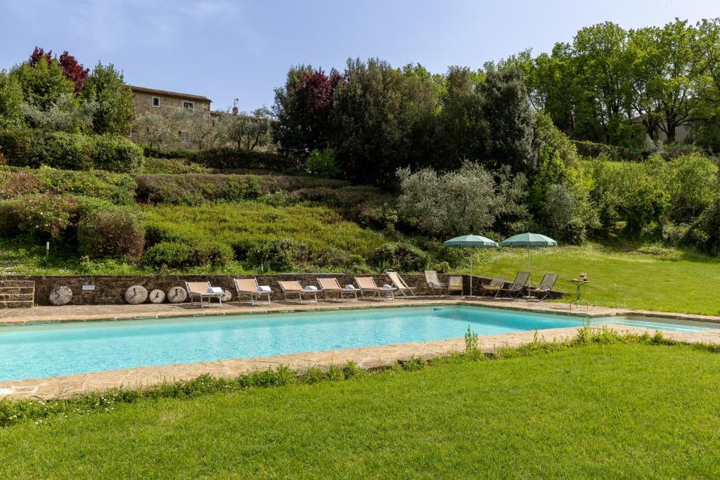 a swimming pool with chairs and umbrellas in a yard at Podere San Bartolo- Casa colonica 3 in Barberino di Val dʼElsa