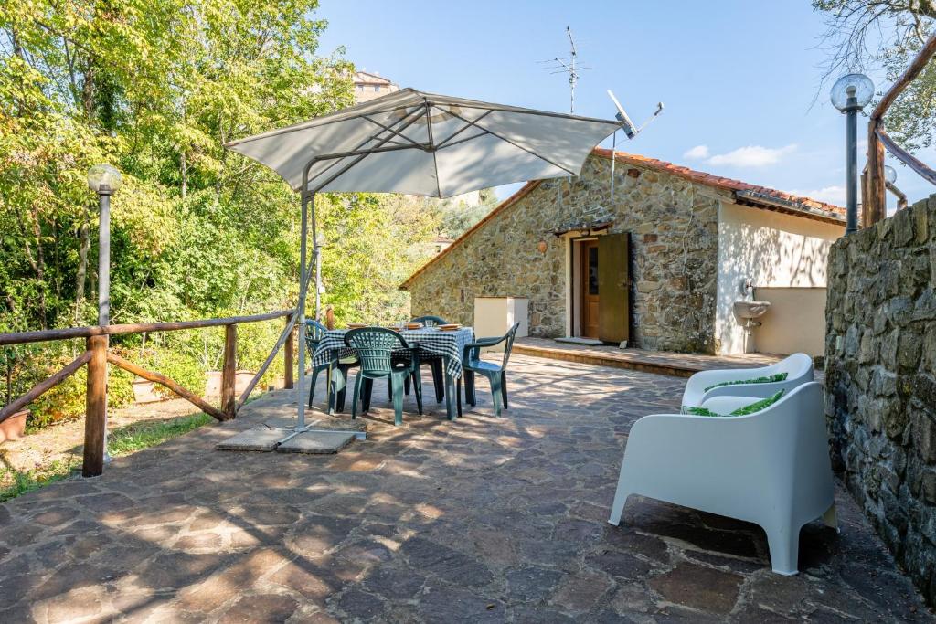 a patio with a table and chairs and an umbrella at Il Colletto Romantic Stonehouse in Pescia