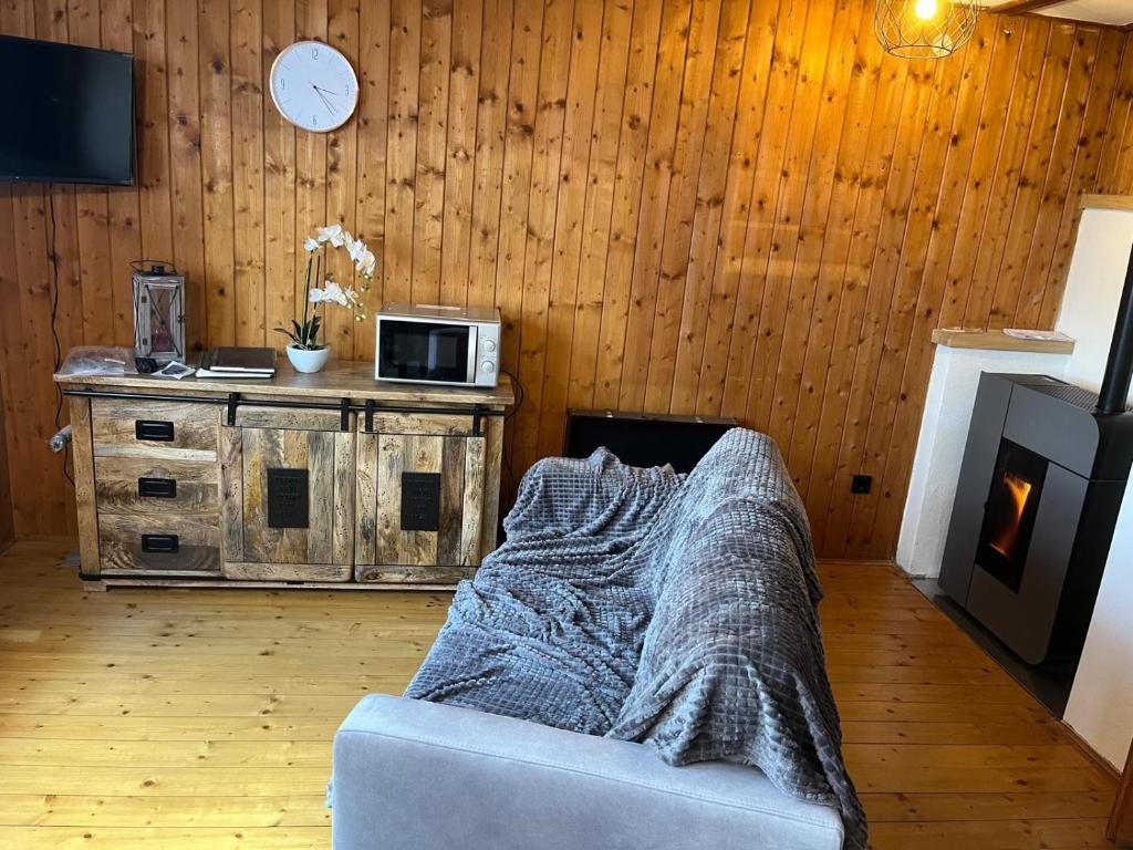 a living room with a couch and a clock on a wall at Urige idyllische Hütte mit Sauna in Grainet