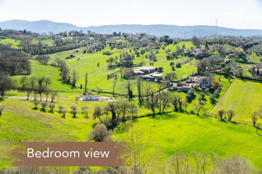 an aerial view of a green field with houses on a hill at Somewhere Over the Hills in Terni