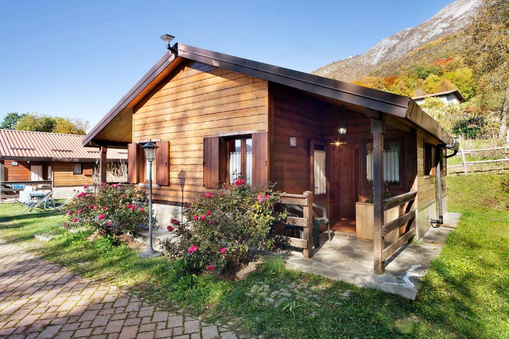 a small wooden cabin with flowers in the grass at Casa Ciclamino in Barzio