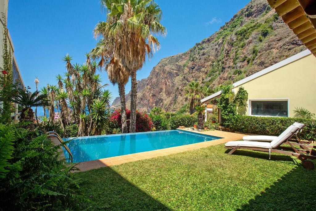 a backyard with a swimming pool and a mountain at Bela Vigia in Jardim do Mar
