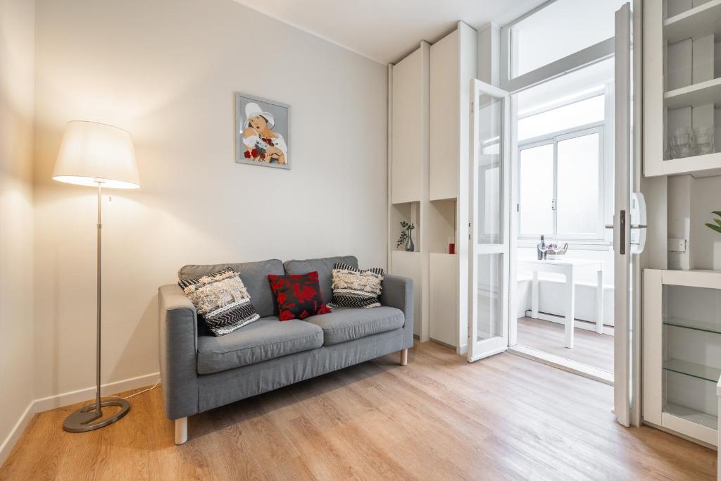 a living room with a gray couch and a window at Sa Babbajola in Cagliari