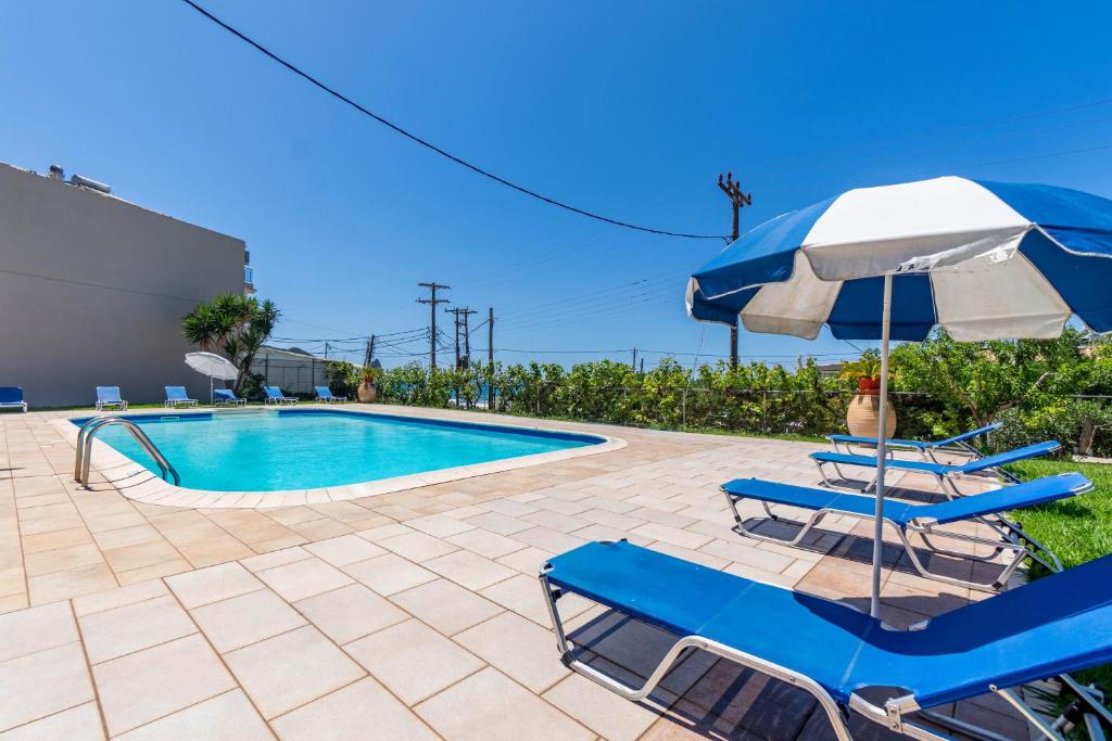 a swimming pool with two chairs and an umbrella at Mires House Side First Floor 8 in Agios Gordios