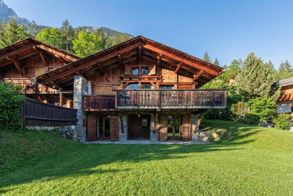 a log home with a deck on a green lawn at Chalet du Brevent ski in - ski out - Happy Rentals in Chamonix
