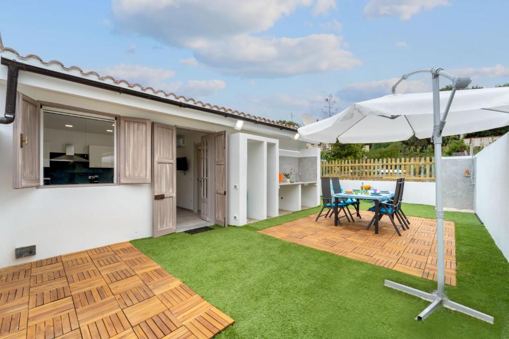 eine Terrasse mit Tisch und Sonnenschirm in der Unterkunft Ikigai in Buggerru