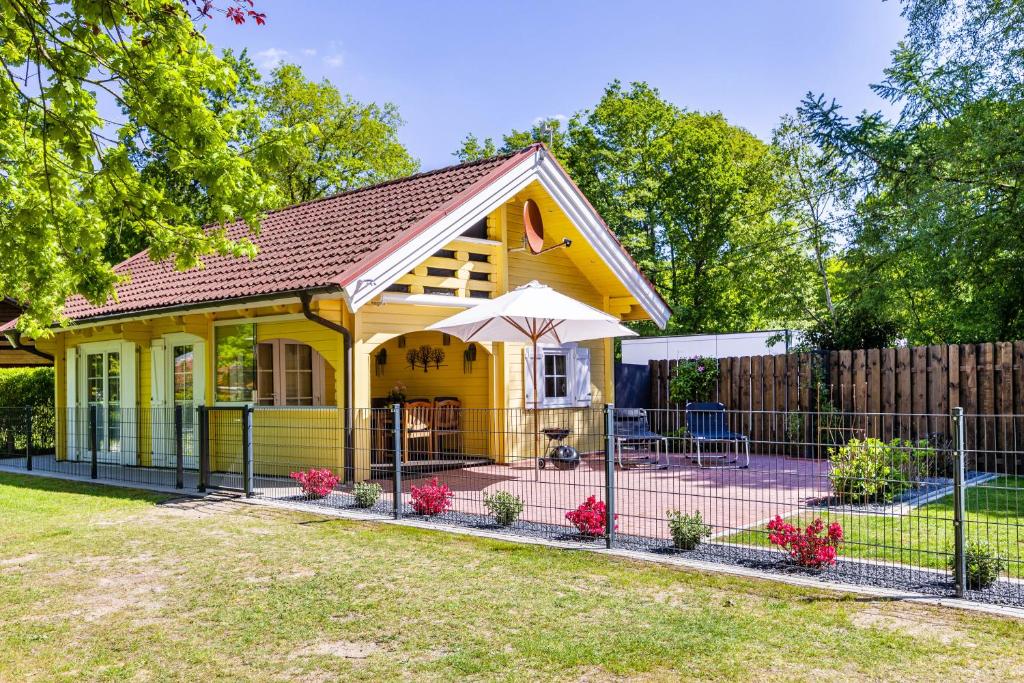 a yellow house with an umbrella in a yard at Haus Miriam in Walchum