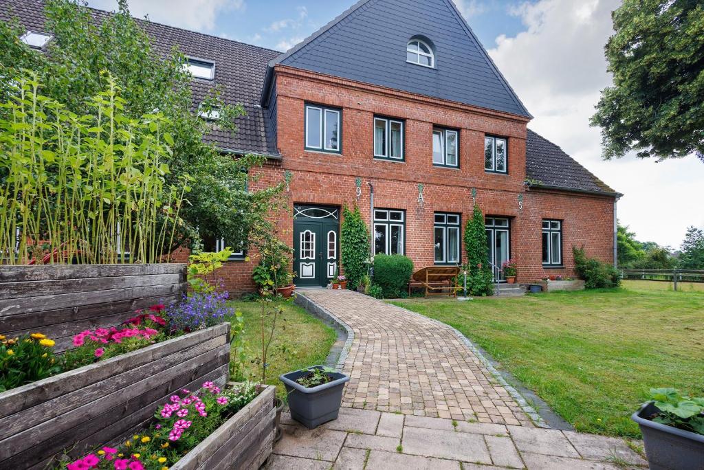 a brick house with a garden in front of it at Reit- und Ferienhof Alte Dorfschule in Holstenniendorf