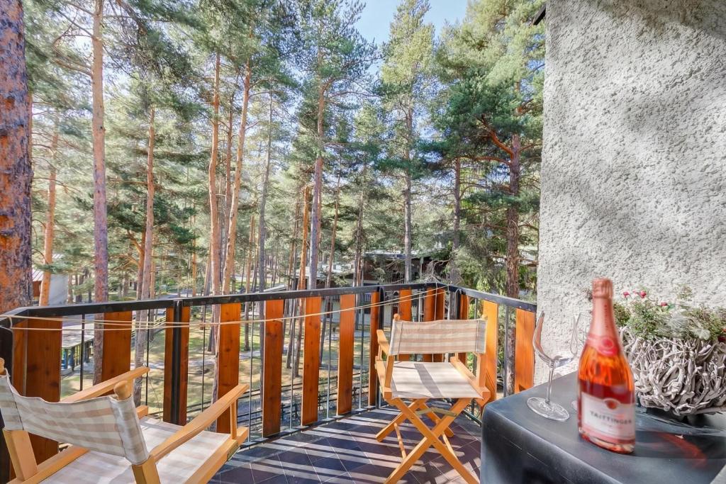 a deck with two chairs and a bottle on a table at Il nido nella Pineta Central in Ski resort - Happy Rentals in Bardonecchia
