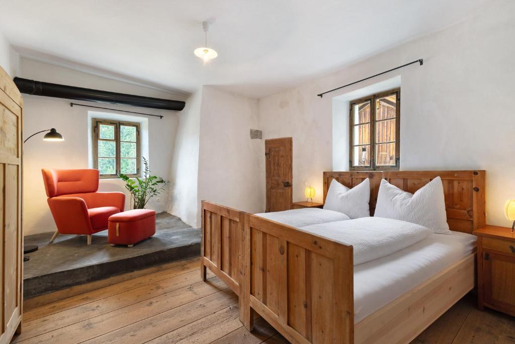a bedroom with a large bed and a red chair at Ansitz Baumannhof Apt Gotik in Falzes
