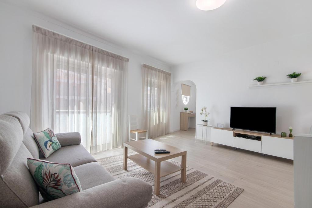a white living room with a couch and a tv at Refúgio Estrela do Mar in Quarteira